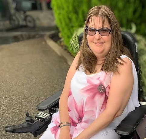 Sarah Lapp, smiling, sitting in her power wheelchair